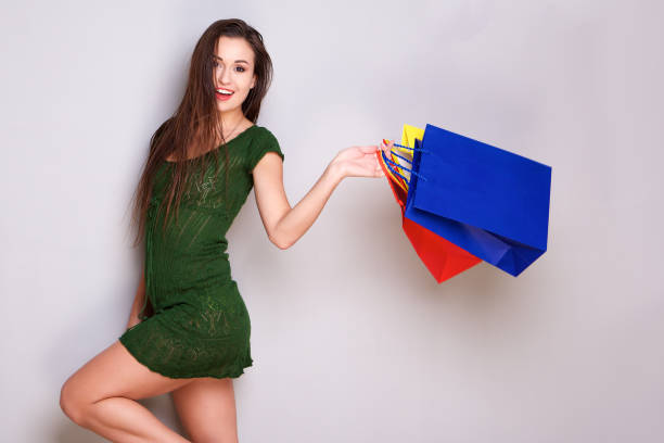 Portrait of happy young woman with shopping bags against gray background