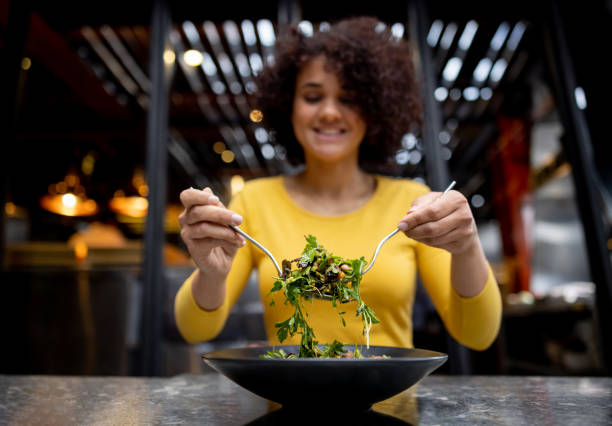 Healthy Latin American woman eating a salad at a restaurant - food and drinks concepts. The benefits of a vegan diet.