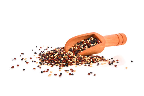 Heap of mixed raw quinoa in wooden scoop isolated on white background. 