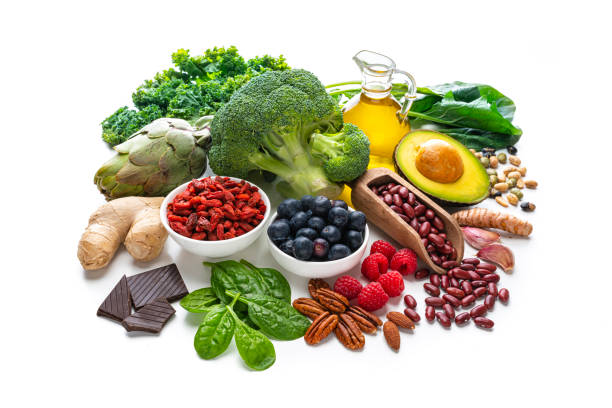 Healthy eating: group of antioxidant food shot on white background. The composition includes healthy fruits, vegetables, nuts and seeds like blueberries, raspberries, goji berries, dark chocolate, artichoke, Kidney beans, ginger, garlic cloves, avocado and olive oil. 