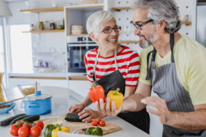 Senior woman and senior man are in the kitchen, they are cooking together.