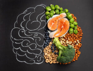 Chalk hand drawn brain with assorted food, food for brain health and good memory: fresh salmon fish, green vegetables, nuts, berries on black background. Foods to boost brain power, top view