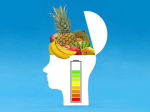 Open head silhouette filled with healthy fruits, the battery indicator shows an increase in performance that results from healthy vegan brain foods